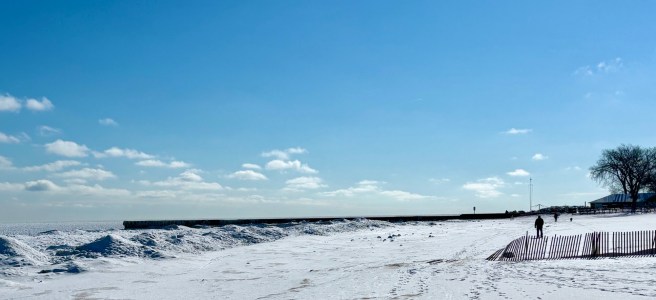 Winter beach scene on Lake Michigan. Snow and solitary figure walking.